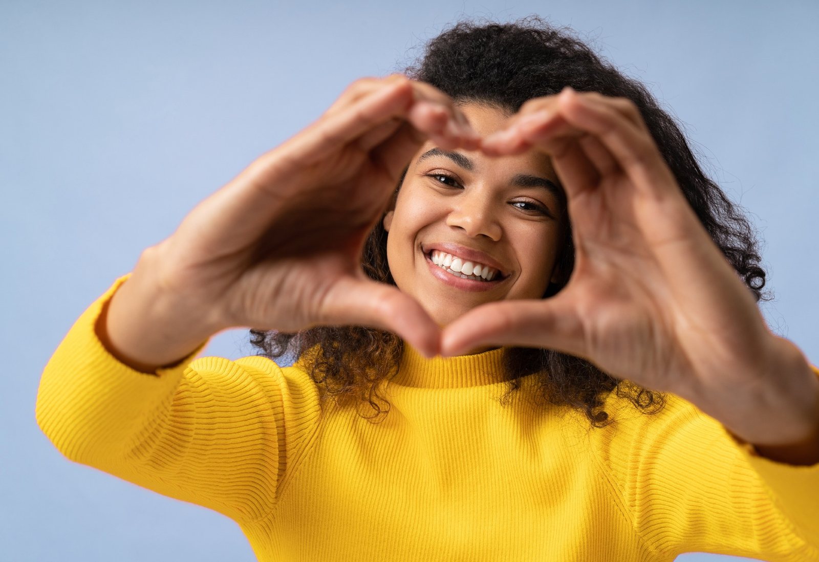 Smiling patient making a heart with her hands after drill-free Curodont cavity treatment at Bloomfield Dental, Drexel Hill PA