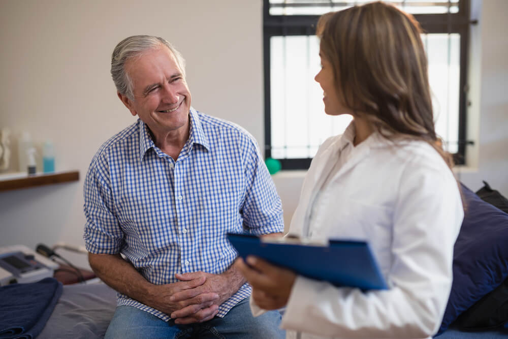 Smiling senior male patient looking at female therapist