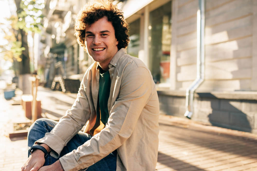 Outdoor image of happy smiling man with curly hair