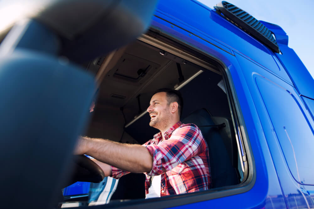 Professional trucker driving truck and smiling