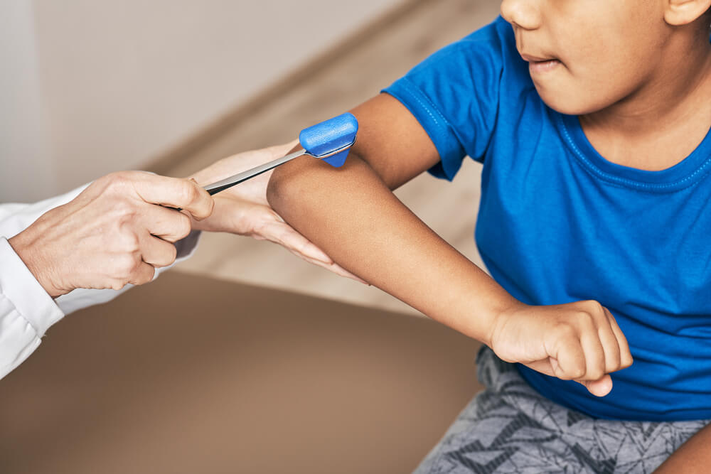 Doctor uses a neurological hammer to check child's hand.