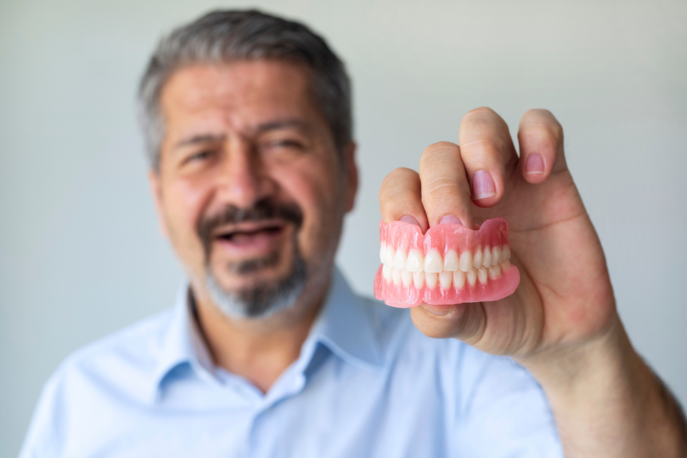 A man holding his new dentures