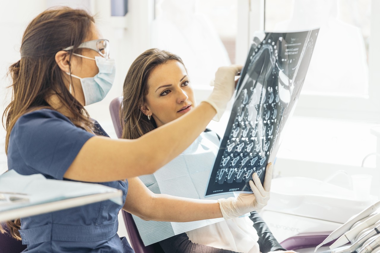 Doctor talking with her patient and teaching a radiograph. Dentist concept.