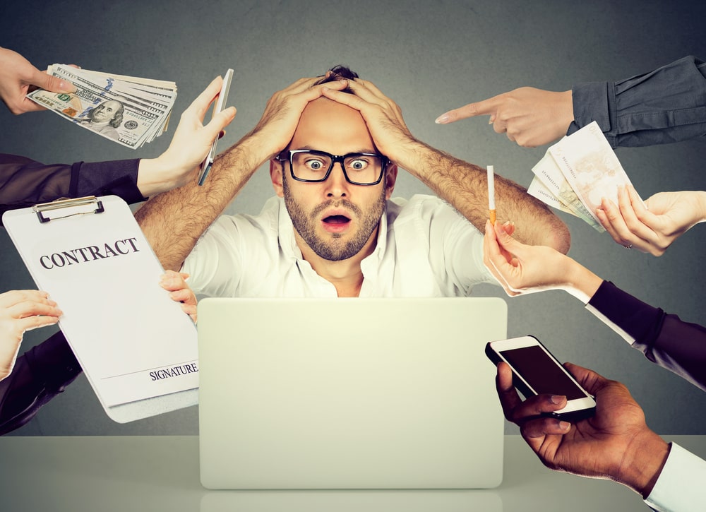 stressed man surrounded by various life stressors