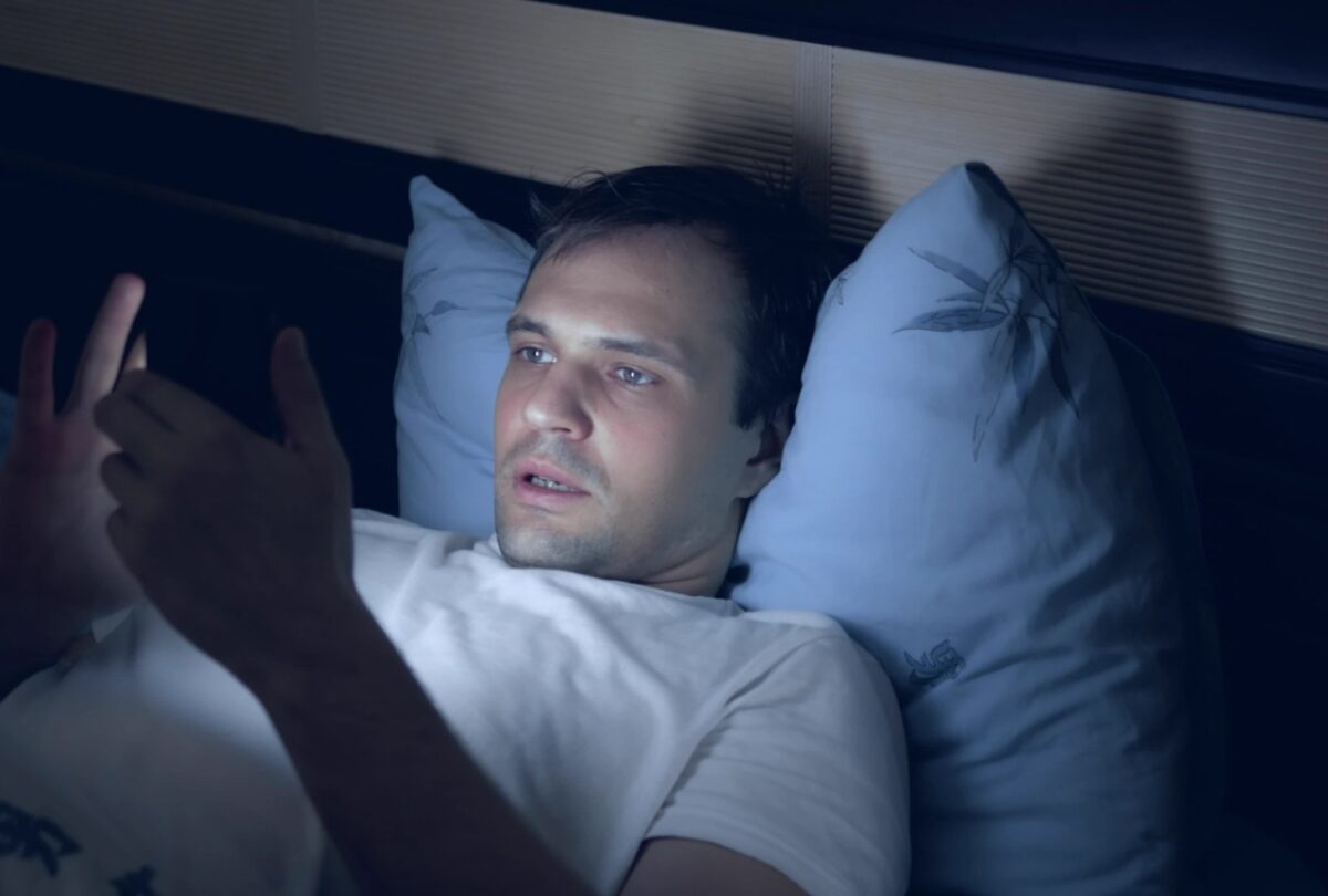 a young man uses a smartphone in bed