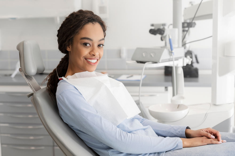 Young lady sitting in dentist chair and smiling