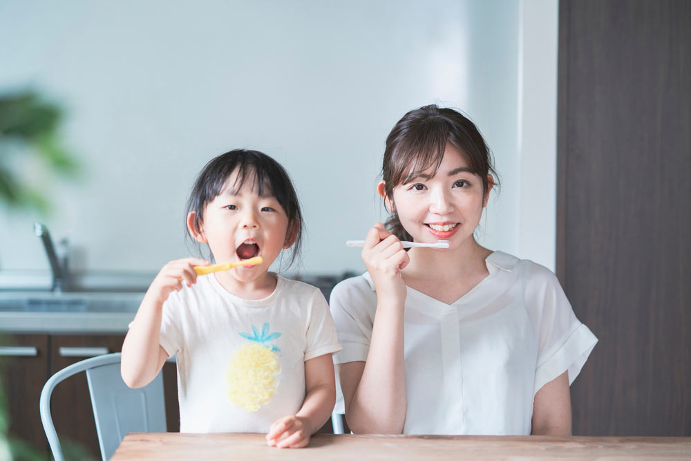 young mom and daughter brushing teeth