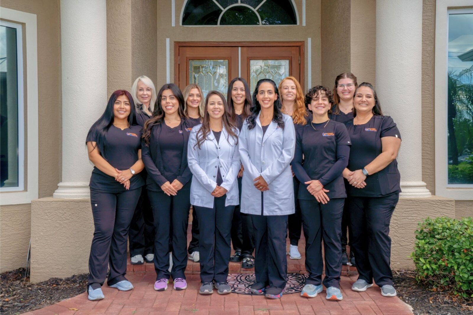 Sunset Harbor Dental team posing at the entrance to their office.