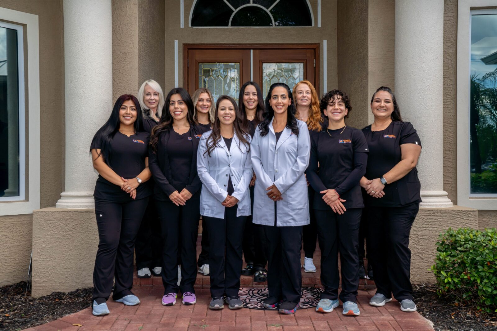 Sunset Harbor Dental Care Team standing on the steps of the Sunset Harbor office