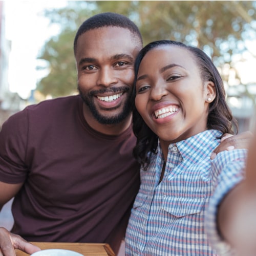 Happy young African couple sitting at table