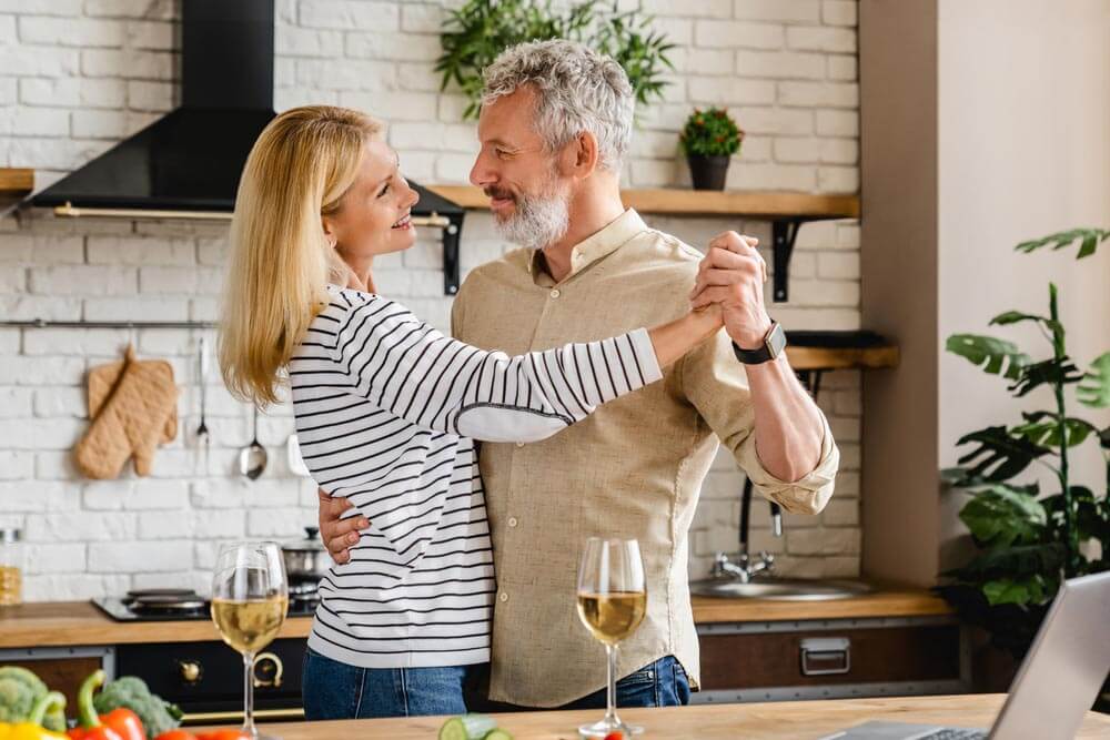 aged couple dancing at home kitchen