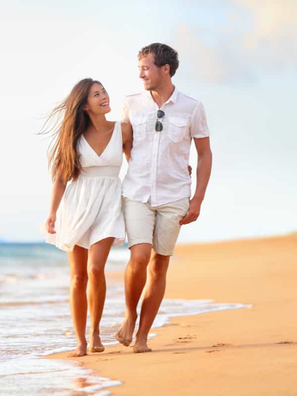 A young couple walk together on the beach.