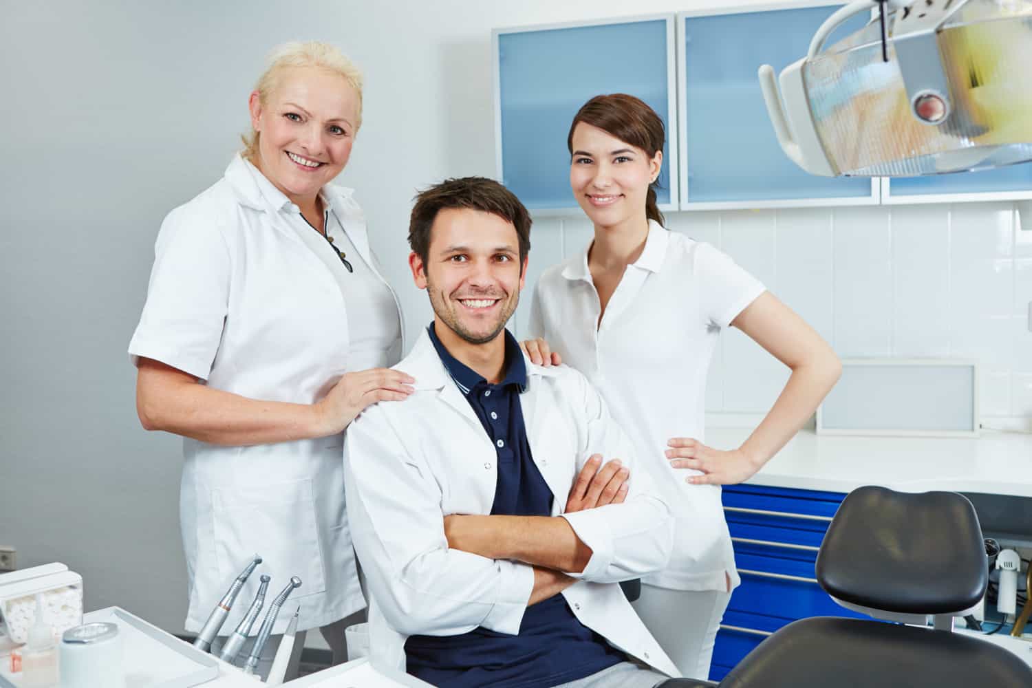 A dentist and two dental hygienists smiling to the camera.