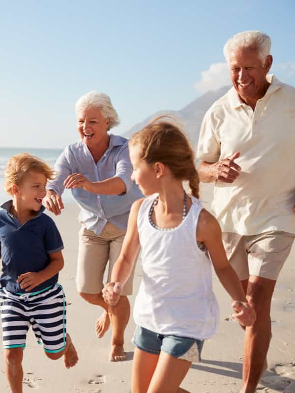 An older couple playfully running after their grandchildren.