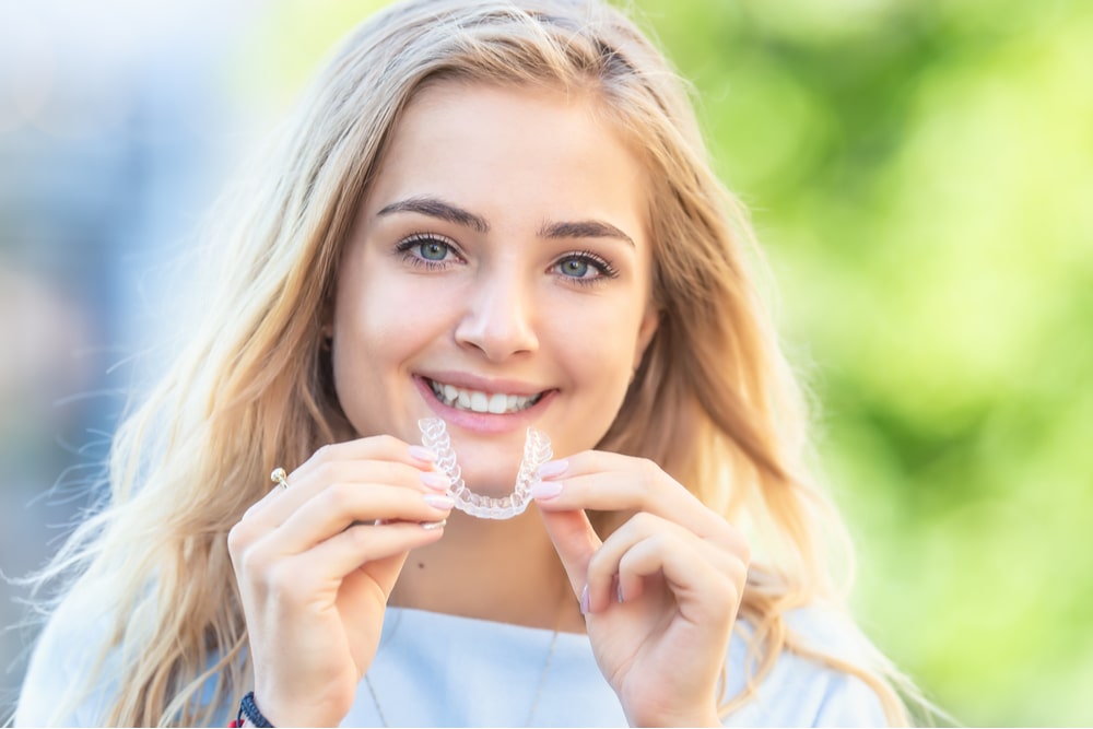 Young attractive woman holding Invisalign