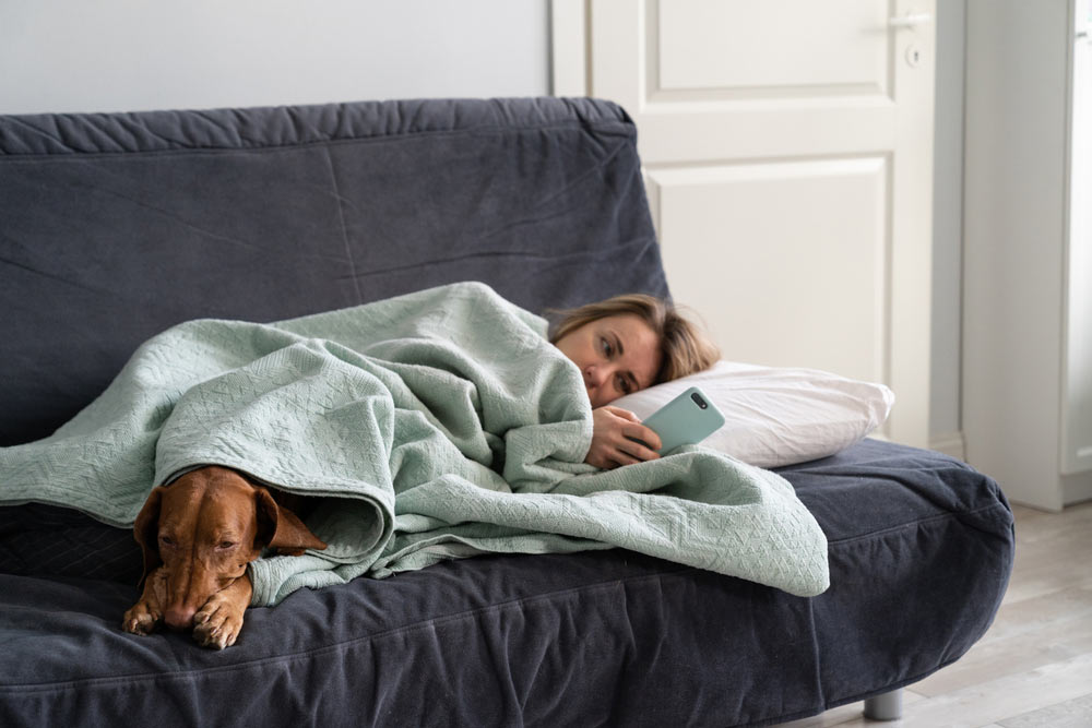 woman lying on sofa with dog