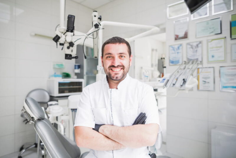 Handsome mature male dentist standing at his clinic