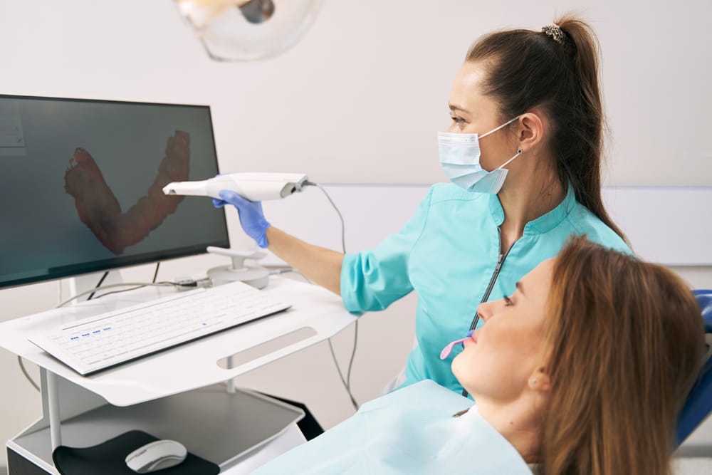 Dentist showing results of dental 3D scanning to woman in clinic