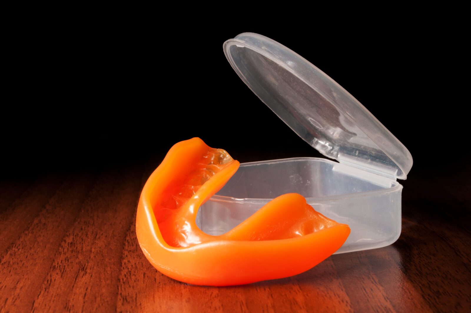 orange mouthguard beside plastic case