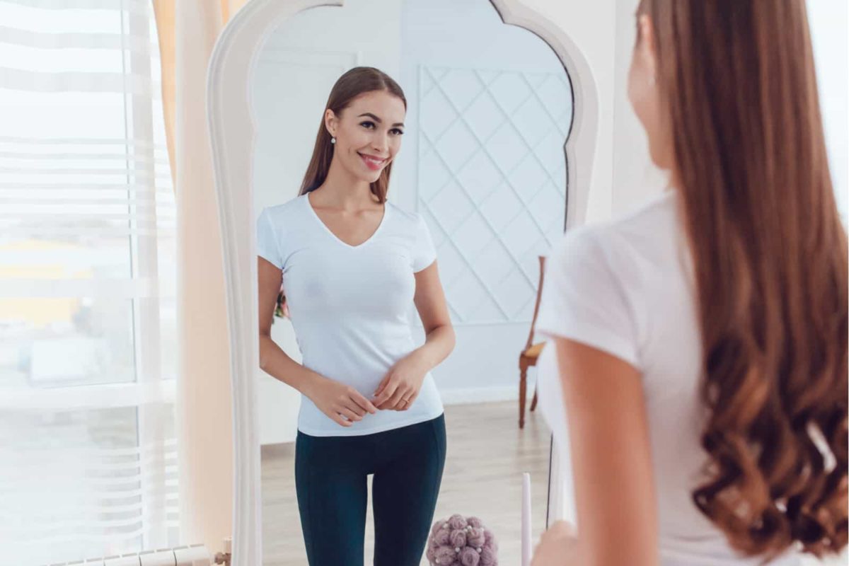 woman smiling in mirror after losing weight