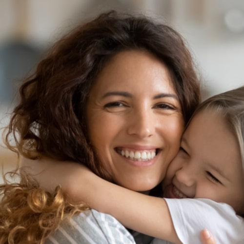 smiling loving mother hugging adorable little daughter