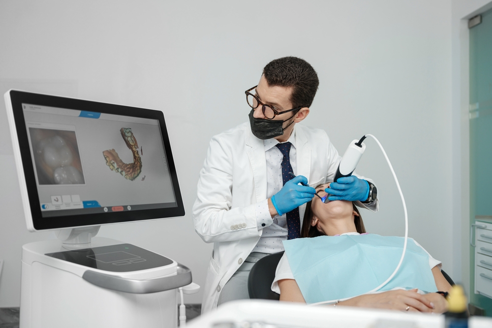 Male orthodontist scaning patient with dental intraoral scanner and controls process on screen