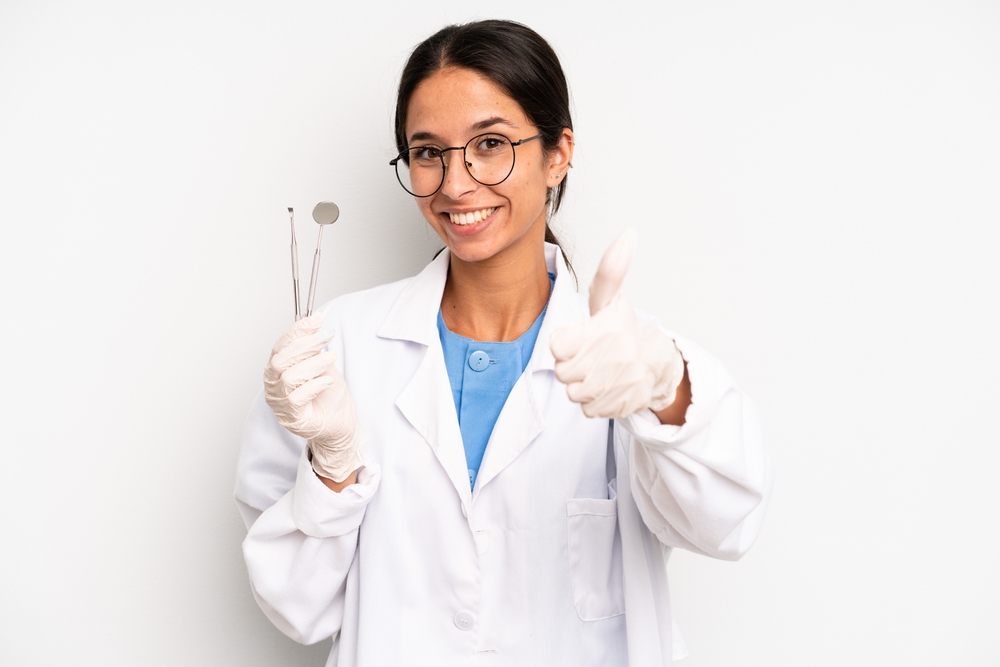 hispanic pretty woman feeling proud,smiling positively with thumbs up. dentist student concept