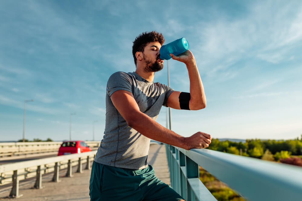 Athlete man drinking water outdoors