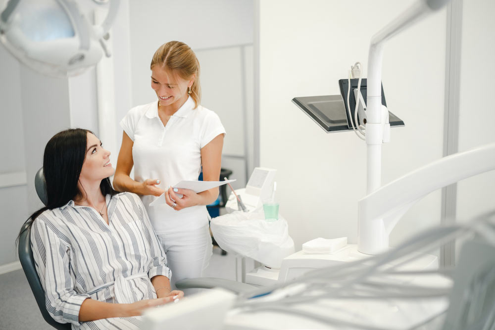 Female dentist talking with patient girl at dental clinic