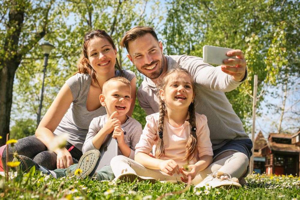 Happy family smiling while taking selfie in park