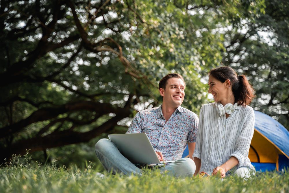 couple having fun use laptop and Camping in the park