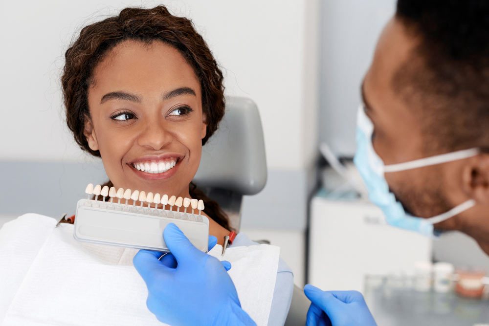 Dentist applying tooth scale samples set to smiling lady