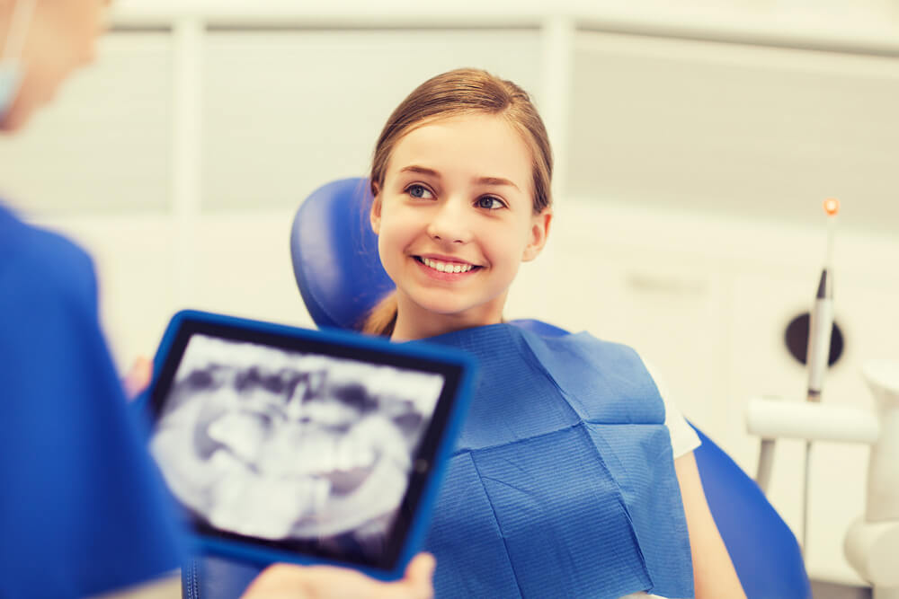 dentist with x-ray on tablet and girl patient