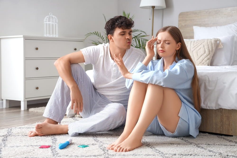 Displeased young woman with husband trying to kiss her in bedroom. Sexual problems concept