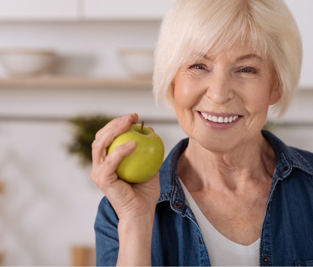 cheerful elderly woman holding an apple