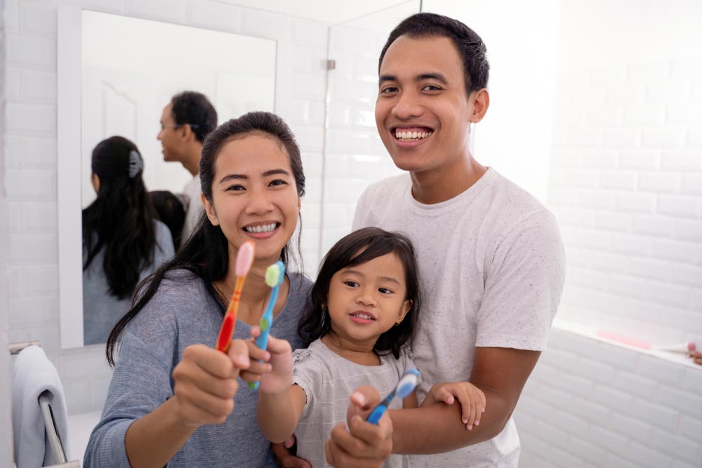 young parent with kid showing their tooth brush