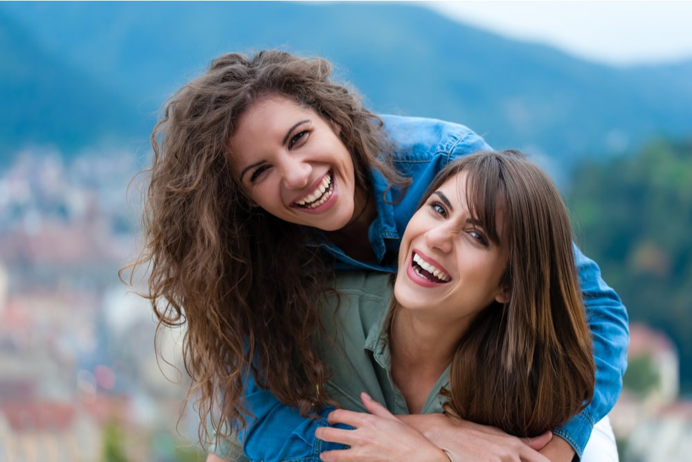 Two women friends laughing and hugging outdoors