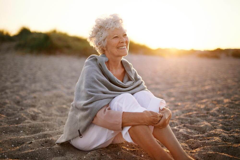 Happy retired woman wearing shawl sitting relaxed