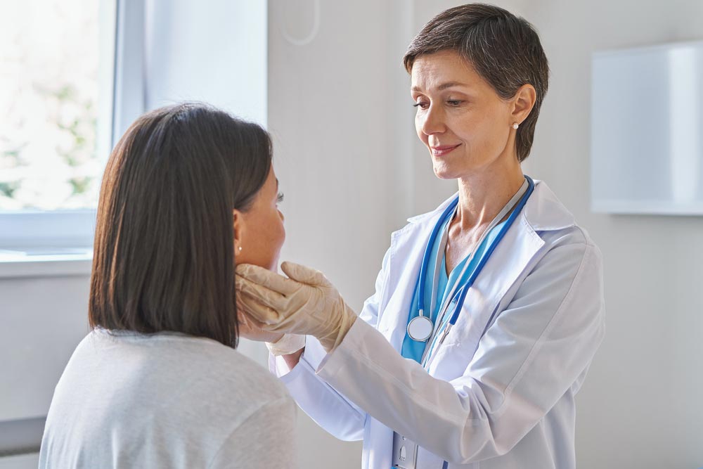 Friendly doctor checking sore throat or thyroid glands