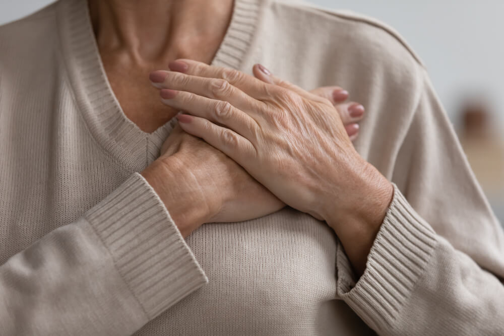 mature senior woman keeping hands on chest