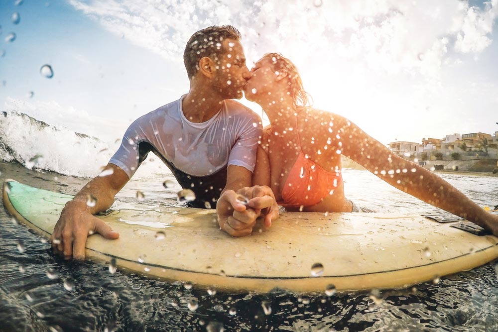 Happy sportive couple surfing in the ocean
