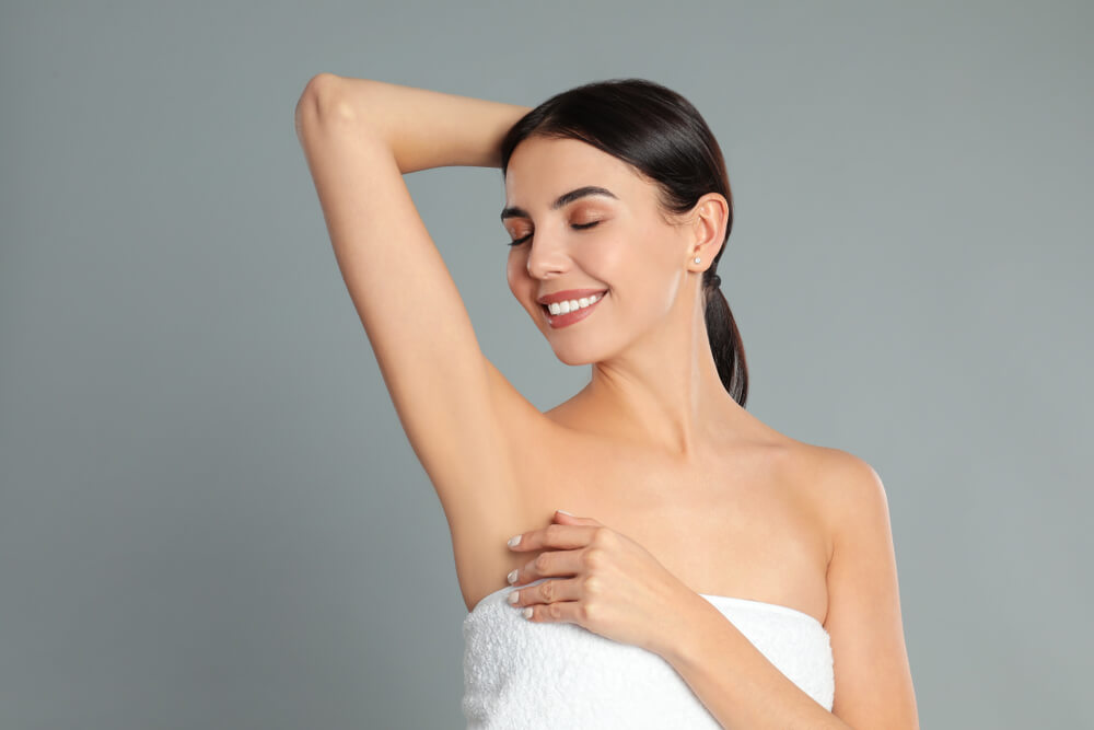 Young woman showing hairless armpit after epilation procedure