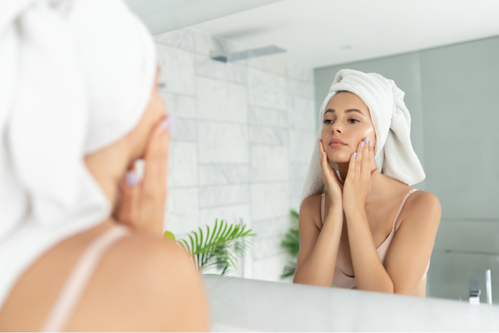 Young beautiful woman using skin face cream moisturizing lotion