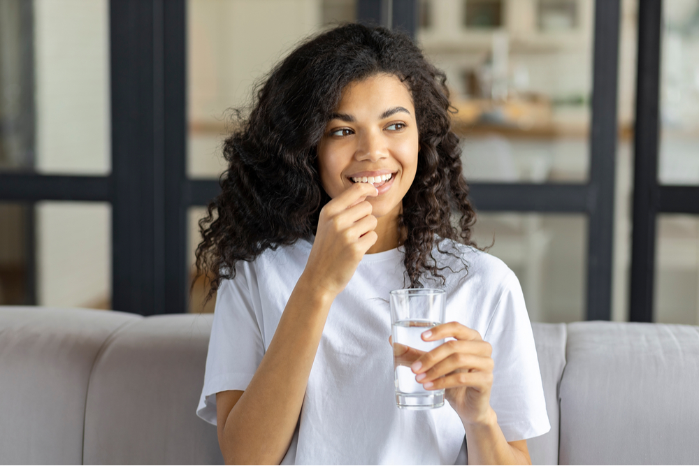 woman holding vitamin pill and glass of water