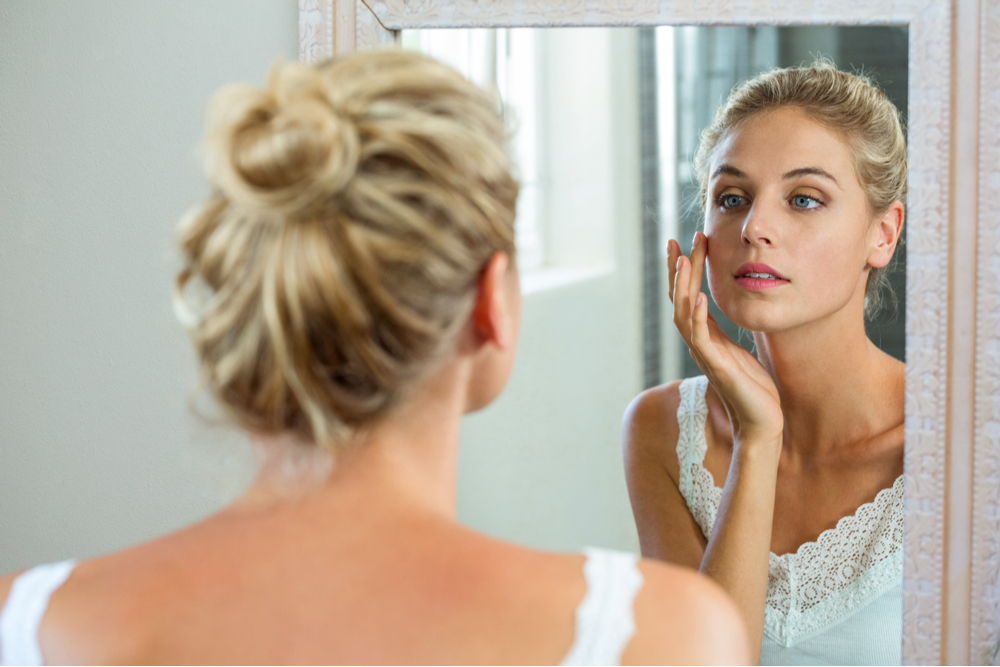 woman checking her skin in mirror