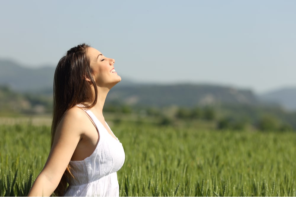 Girl celebrating no stigma while breathing fresh air in a green wheat meadow