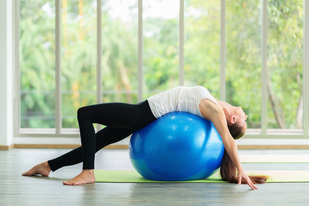 woman practicing yoga working out with ball