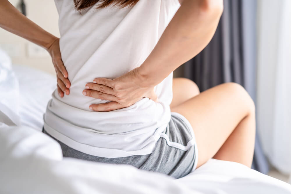 Woman suffering from back ache on the bed