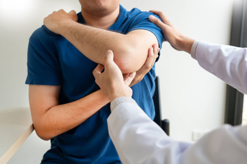 Doctor examining patient suffering from shoulder pain