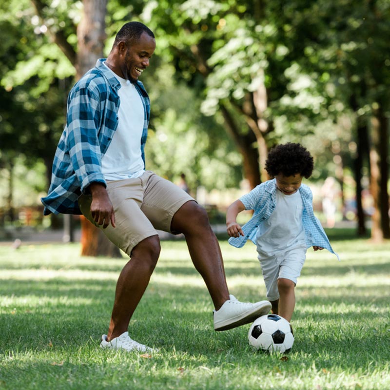 happy man playing football with curly son